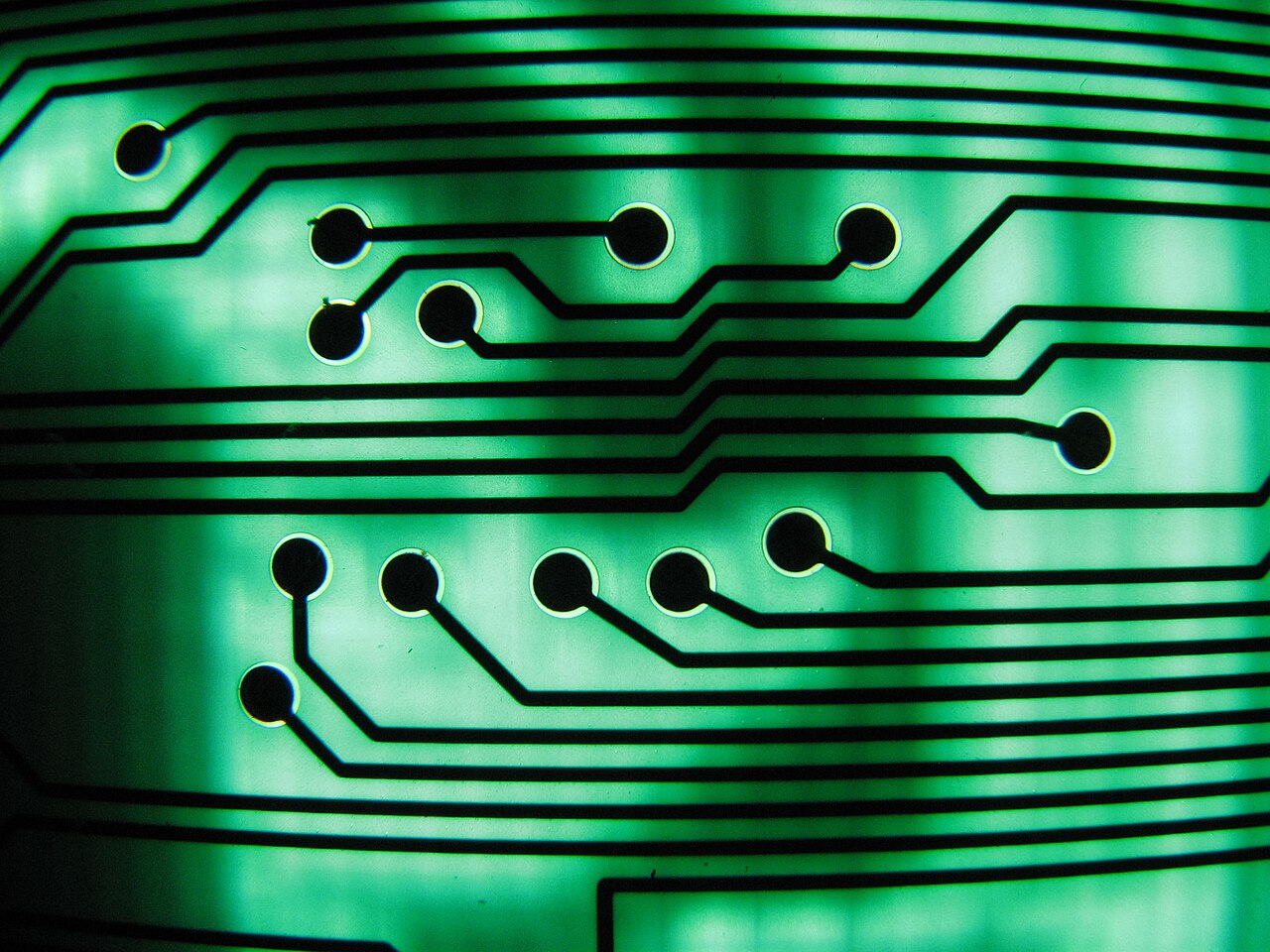 Green circuit board with illuminated traces under magnification