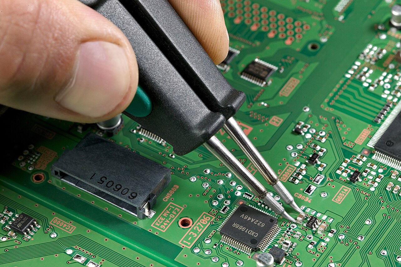 Technician soldering a small component on a green circuit board
